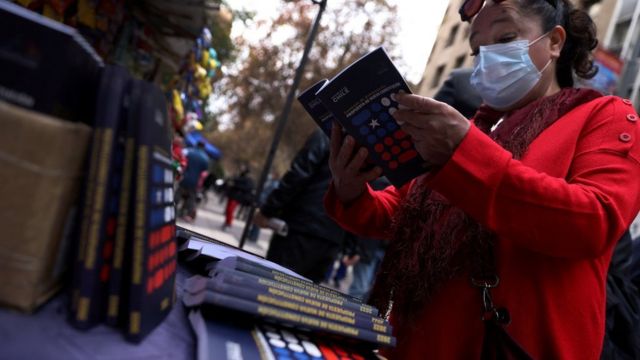 Una mujer sostiene un ejemplar del proyecto de nueva Constitución