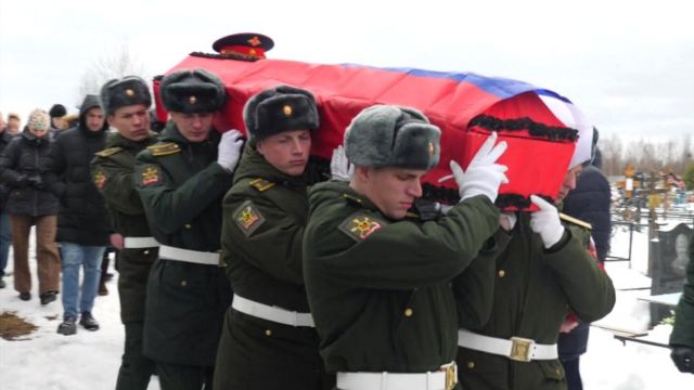Militares russos carregam caixão envolto na bandeira nacional pelo um cemitério com neve
