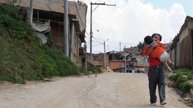 Un niño carga en brazos a otro niño en un barrio de Bogotá.