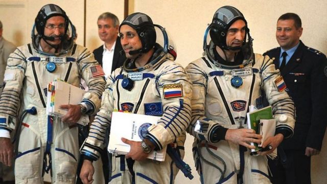 Astronautas de países diferentes sorriem enquanto conversam