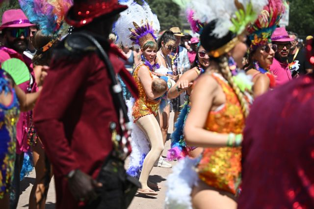 A dancer from a carnival samba band breastfeeds as they parade through the festival site on Day 4 of Glastonbury Festival 2023 on 24 June 2023 in Glastonbury, United Kingdom. 
