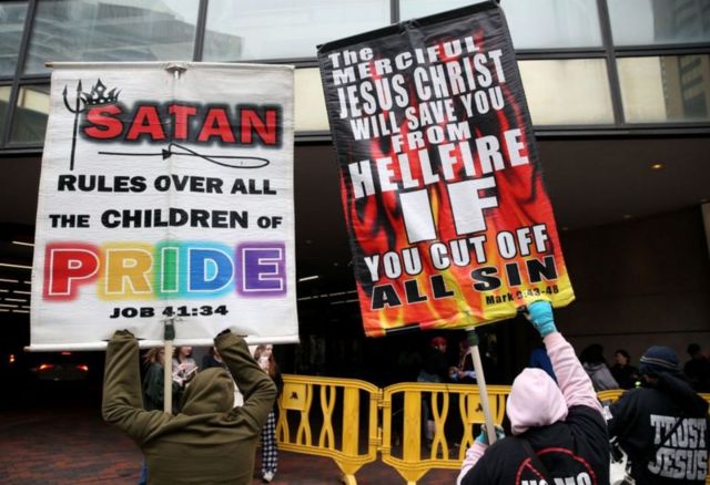 Manifestantes exibiram cartazes no lado de fora do hotel onde se realizava a SatanCon em Boston, nos Estados Unidos