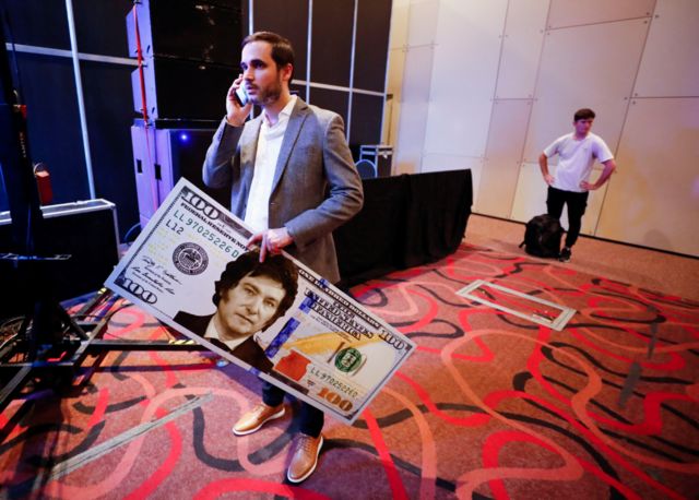 Un partidario de Milei con un billete enorme de US$100 que lleva impreso el rostro del candidato libertario.