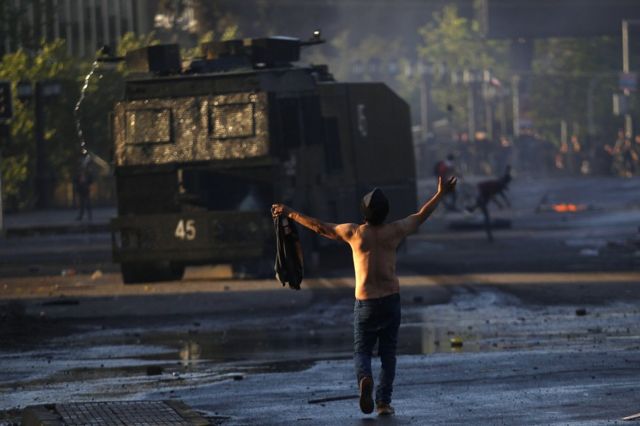 A man confronts a tank at protests in Chile