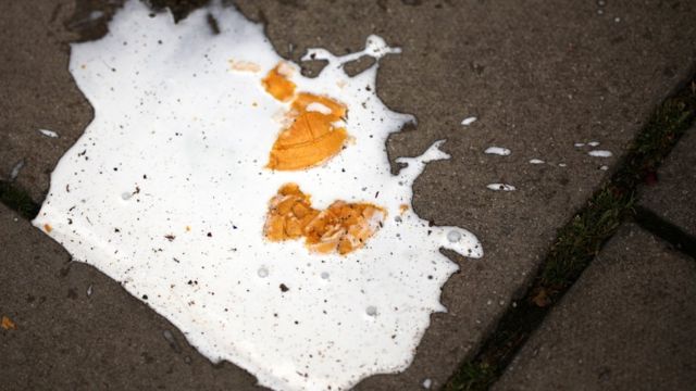 An ice cream melting on the pavement after it has been dropped to the ground.