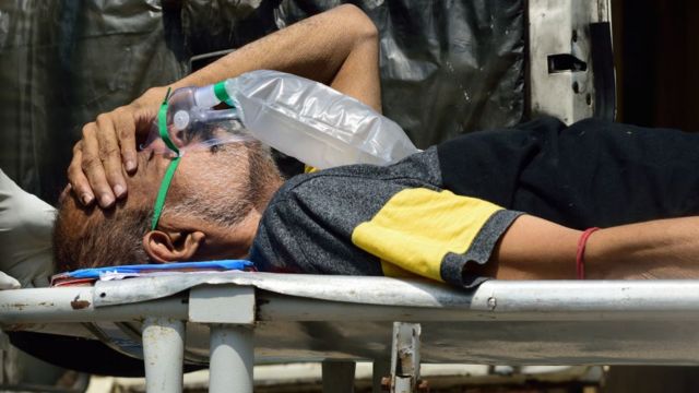 Um paciente de covid-19 usando uma máscara de oxigênio médica sendo carregado em uma maca para um hospital antes da internação em Calcutá, na Índia, em 24 de abril de 2021