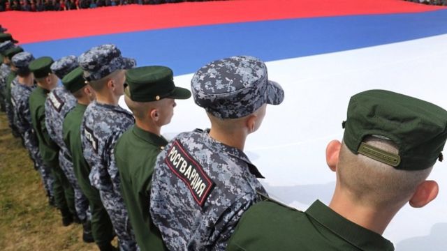 Des soldats russes tiennent un énorme drapeau russe pour marquer la Journée du drapeau national russe à Moscou, en Russie, le 22 août 2022