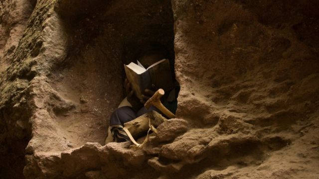 Один из паломников устроился в небольшой пещере и читает Библию