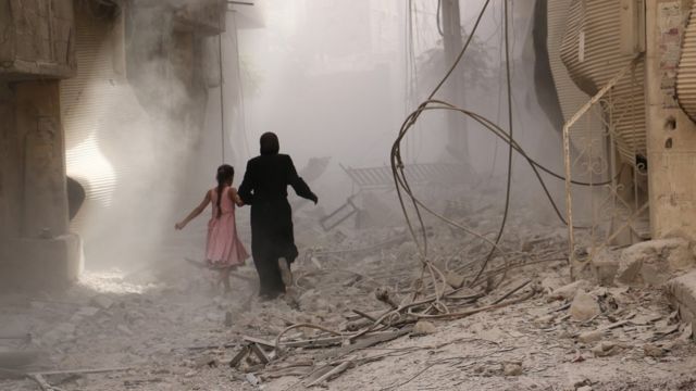 Una mujer corre por las calles demolidas de una ciudad siria.