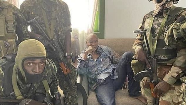 身着牛仔裤和印花衬衫的孔戴被军人包围。(photo:BBC)