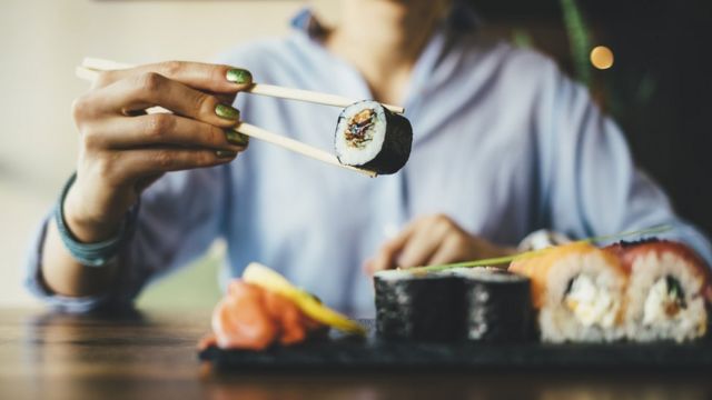 Mulher comendo sushi