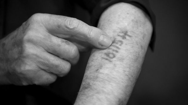Hombre enseñando el número que le tatuaron en un campo de concentración