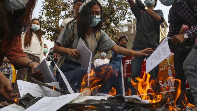 Protesters burn copies of the constitution.