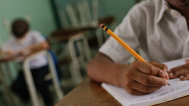 Un niño escribiendo en su pupitre