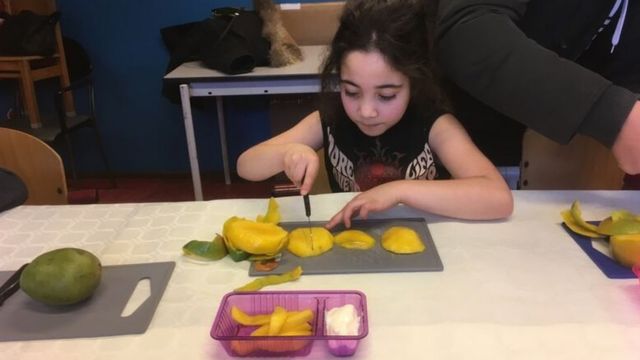 Una niña pica fruta en un centro comunitario de Ámsterdam