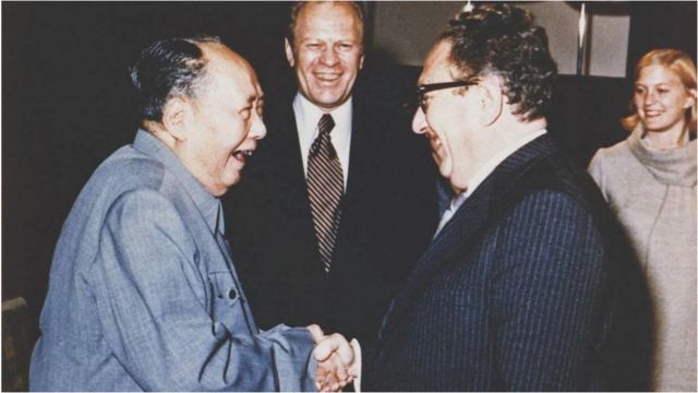 1975年访问北京时，毛泽东和基辛格握手，福特总统（中）当时站在身旁看着。