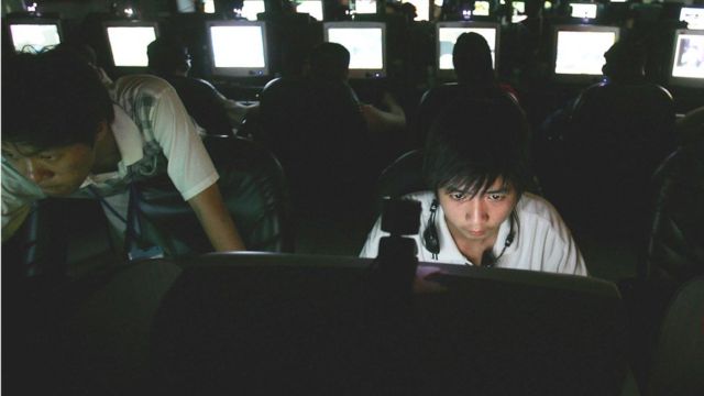 Joven asiático frente a computadoras.