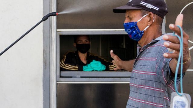 Un hombre se desinfecta antes de entrar a un negocio en Maracaibo.