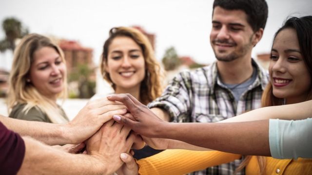 Grupo de hombres y mujeres juntando sus manos.