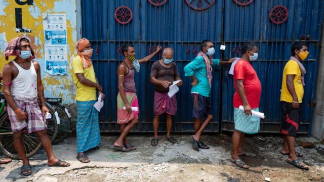 Daily wagers wait in a queue for vaccination at the 'Vaccination on wheels' in Kolkata. A bus was turned into a COVID vaccination centre to curb the surge in COVID-19 cases in India.