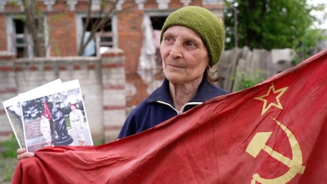 安娜拿着她的红旗和宣传她的照片。(photo:BBC)