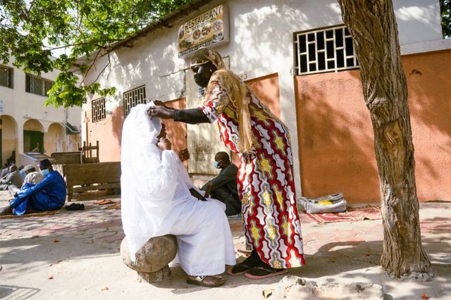 امرأة تساعد أدجا أسيزي في تعديل حجابها