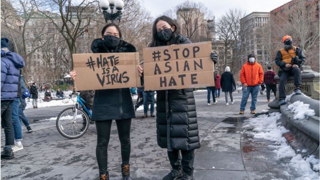 Two people holding stop Asian hate signs