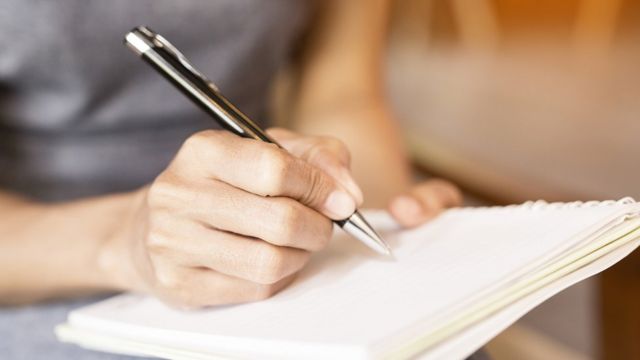 Una mujer escribe en un cuaderno