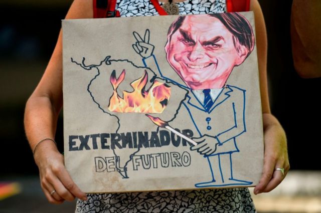 'Exterminador do futuro', diz cartaz que mostra Bolsonaro com um palito de fósforo, incendiando a Amazônia. Cali (Colômbia), agosto de 2019