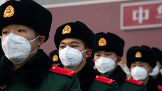 Quatro militares chineses com máscaras e enfileirados