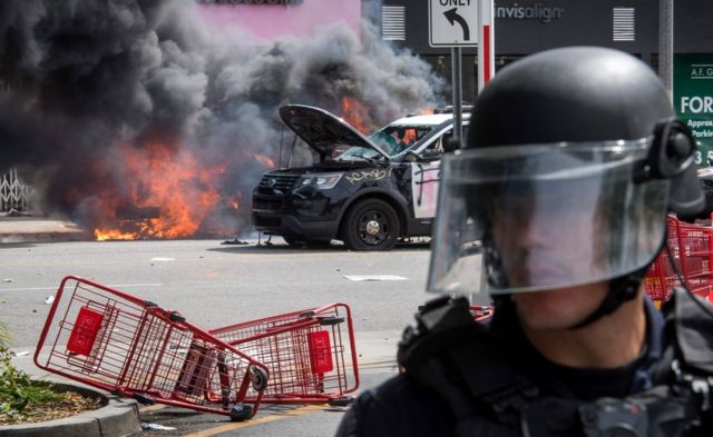 Police vehicles burn after being set on fire by demonstrators in the Fairfax District of Los Angeles as they protest the death of George Floyd, 30 May 2020