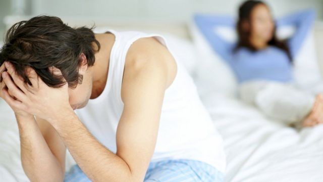 Homem sentado na beira da cama