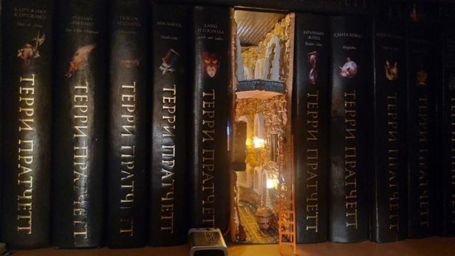 Un pequeño diorama de un callejón visible entre los libros en una estantería