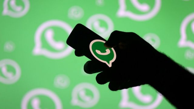 Mão segurando celular com símbolo do WhatsApp