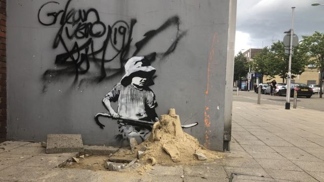 벽화 속 아이가 도로에 방치된 모래와 어우려져 있다