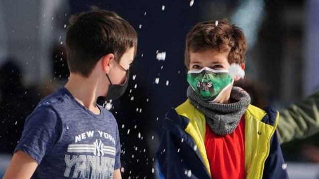 Meninos com máscaras brincam na neve