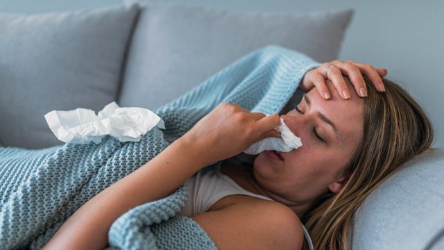 Mujer recostada con síntomas de gripe