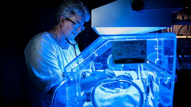 Médica examinando bebê em incubadora