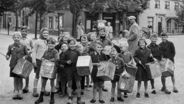 Niños con latas de galletas vacías en las calles de Amsterdam, alrededor de 1944.