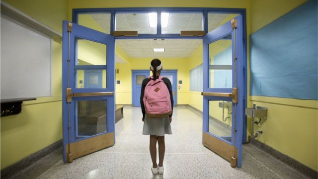 Una estudiante camina por el pasillo de una escuela.