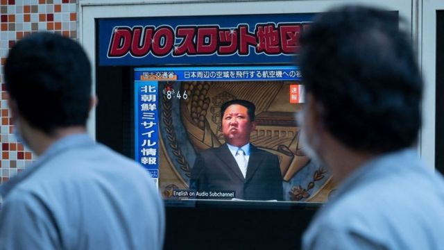 People in Tokyo walk past a television screen showing Kim Jong-un