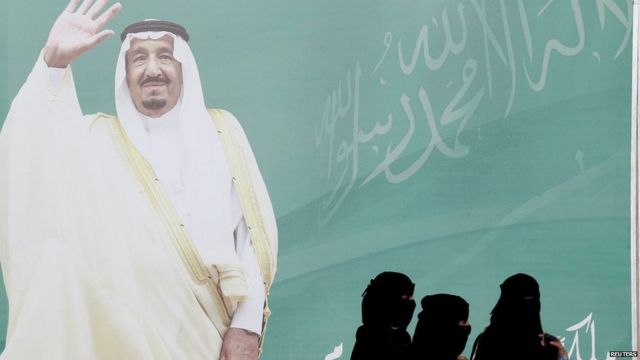 File photo showing women walking past a photo of Saudi Arabia's King Salman in Riyadh (12 February 2018)