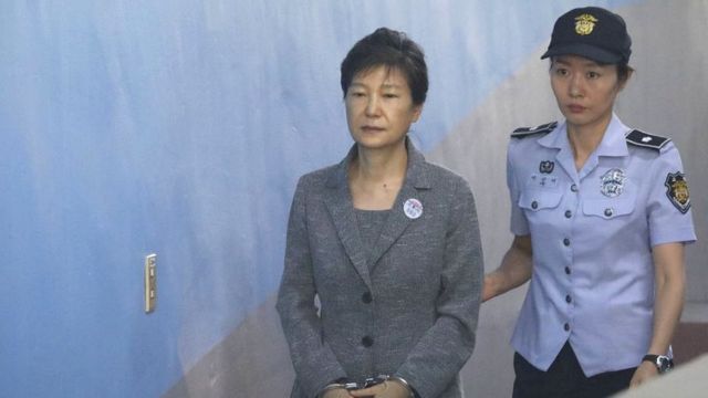 Park Geun-hye em corredor, ao lado de policial