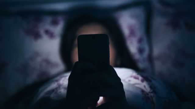Pessoa usando celular na cama
