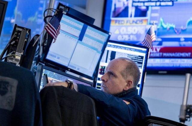 纽约证券交易所，一名交易员在看着屏幕上显示有关美联储决定加息的消息。(photo:BBC)