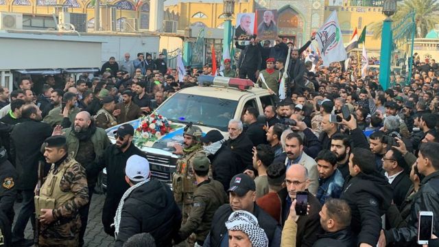 Crowds gather around a vehicle at the funeral of Qasem Soleimani in Baghdad