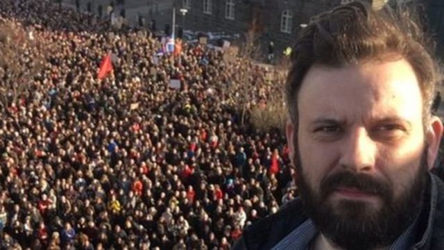 футболист Рагнар Ханссон на фоне толпы протестующих