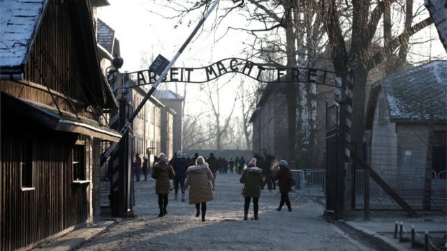 Pessoas diante de portão de Auschwitz
