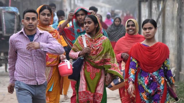 Trabajadores camino a casa tras terminar su turno laboral en una fábrica de confección en Daca, febrero 2020