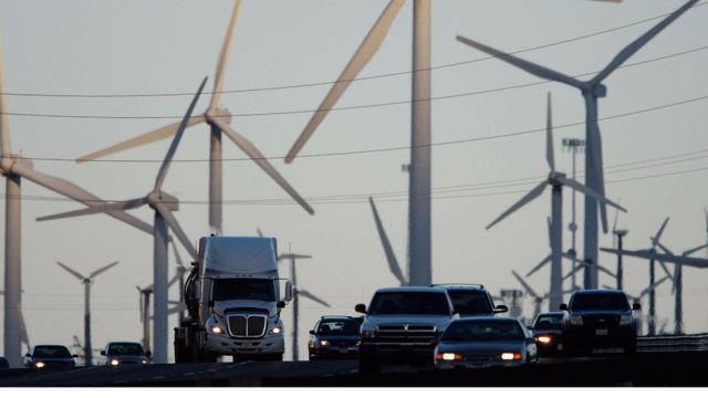 Camiones y vehículos entre molinos de energía eólica.